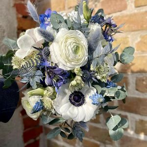runder Brautstrauß mit weißen Ranunkeln, weißen Eustoma, Rittersporn, Muskari, Nigella, Astrantia, Eukalypthus